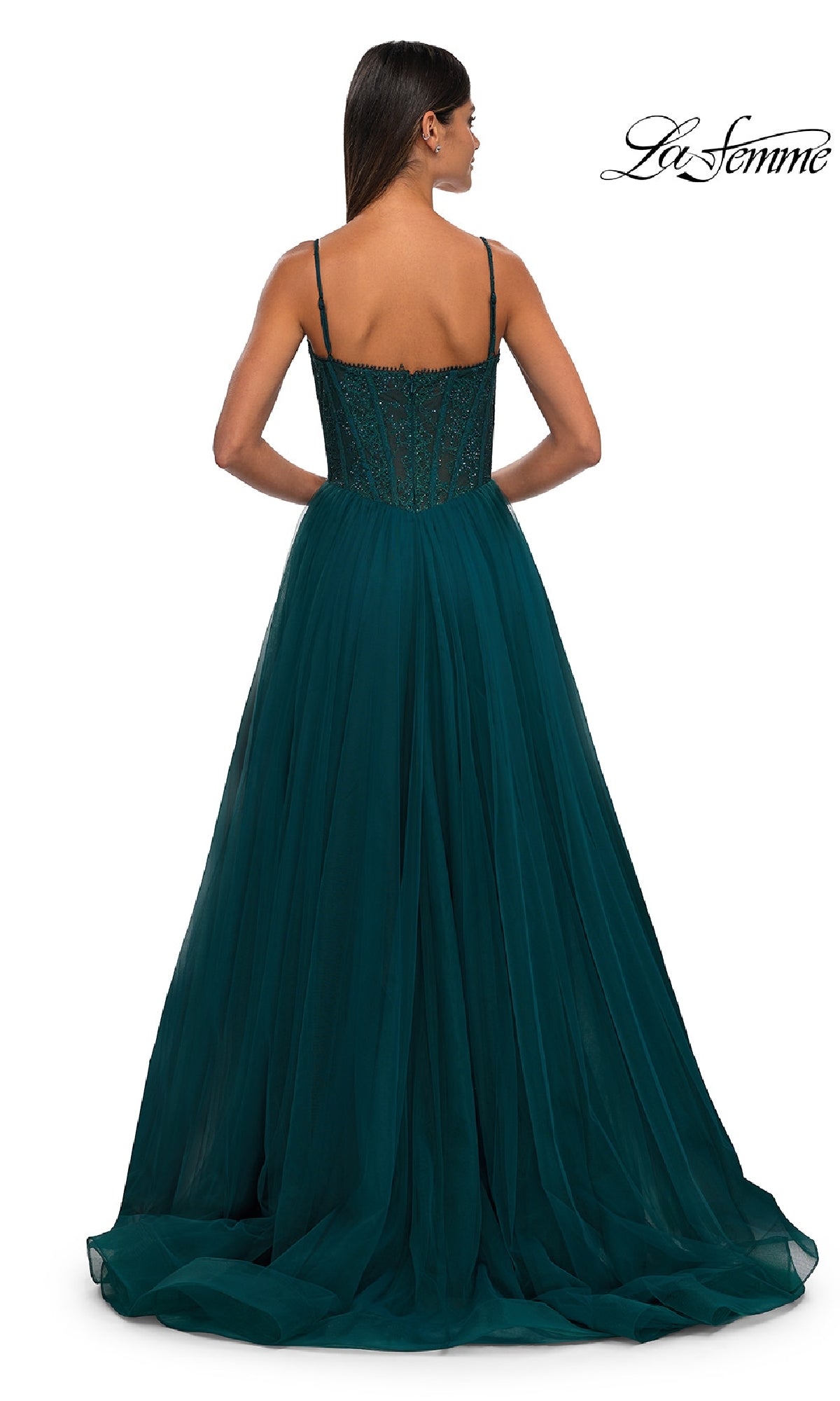 A woman in a dark teal Beaded-Bodice Long Prom Ball Gown, La Femme 32594, with thin straps and a fitted embellished bodice stands facing away. The floor-length dress features a full tulle skirt and the La Femme logo is visible.